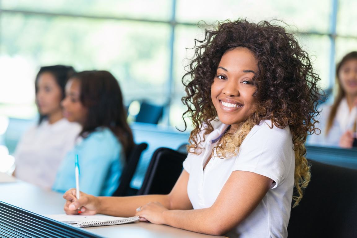 African American college prep school student taking notes during class