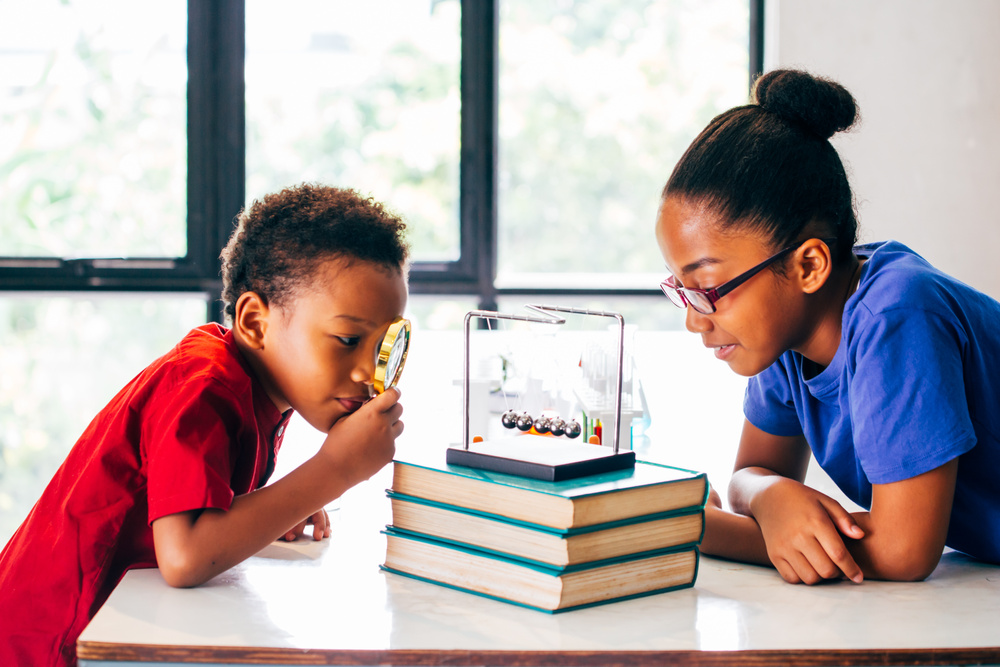 Two African American Mixed Kids Using a Magnifying Glass and Pul