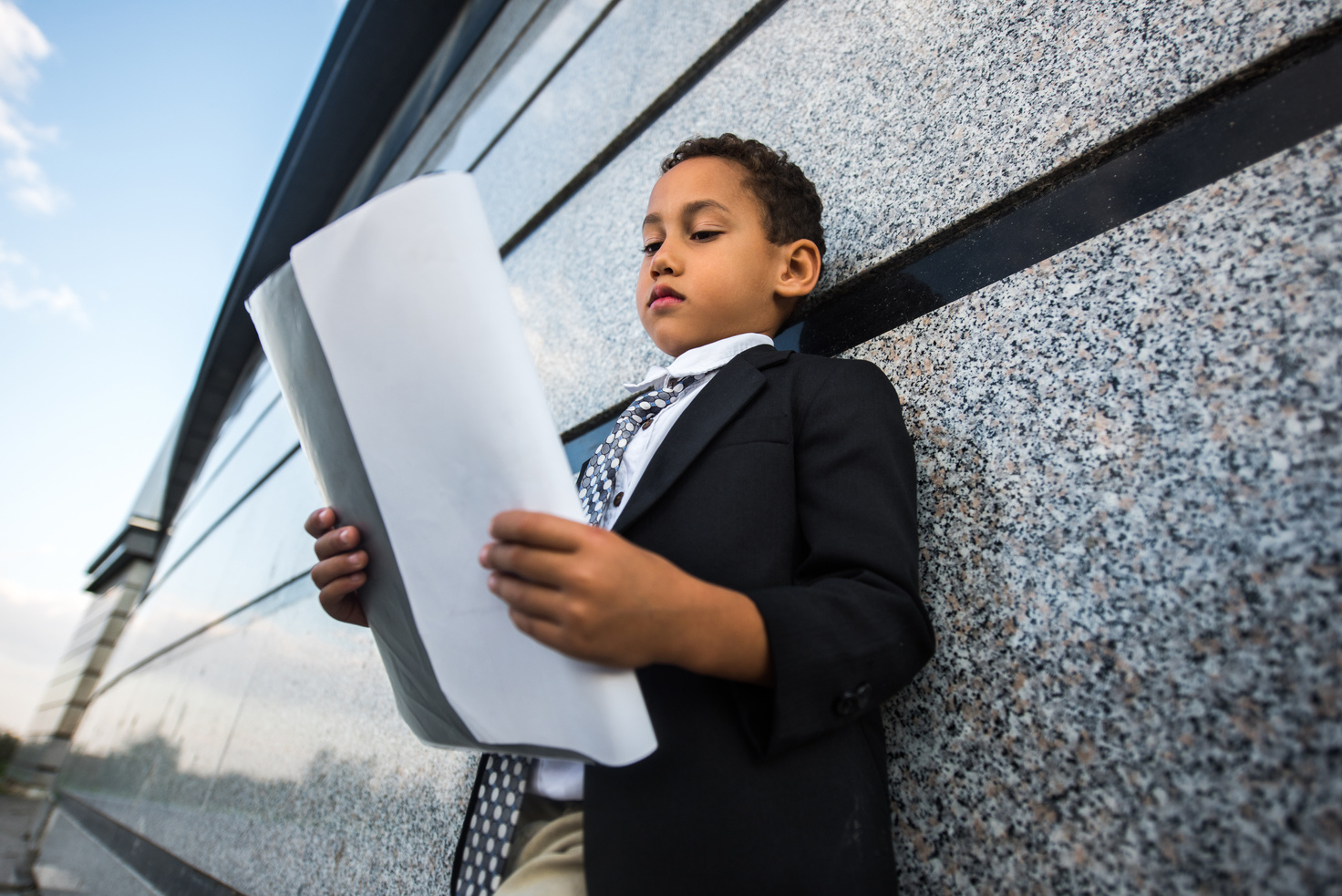 Serious African American business kid reading reports outdoors.