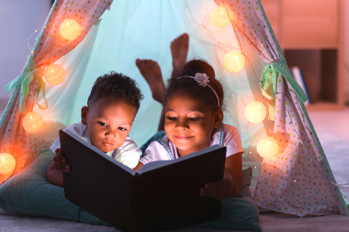 Little African-American Children Reading Bedtime Story in Hovel